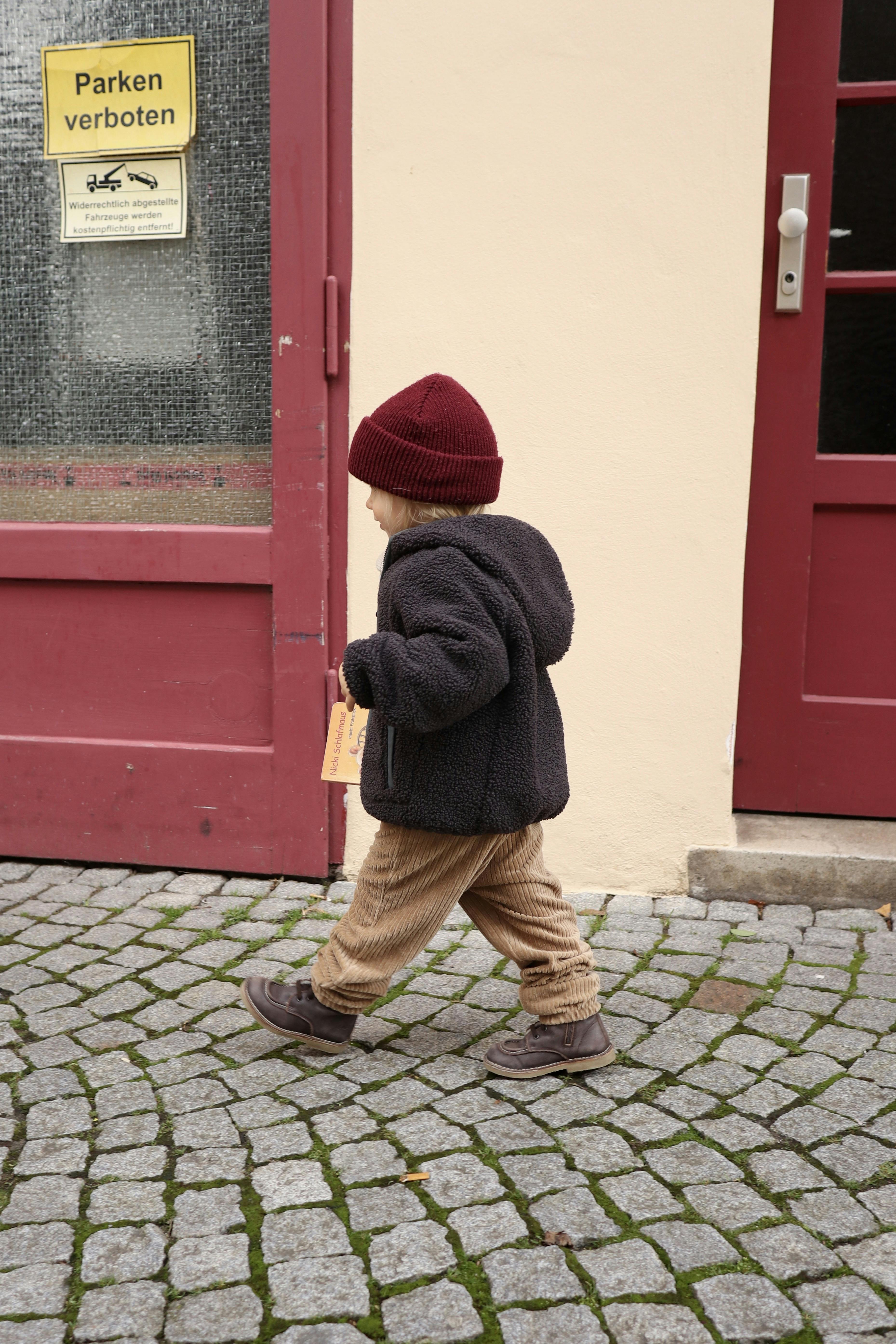 Kind von der Seite beim Laufen mit farblich zur Mütze passenden Türen.